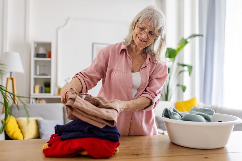 Senior folding clean laundry at home to maintain independence and comfort